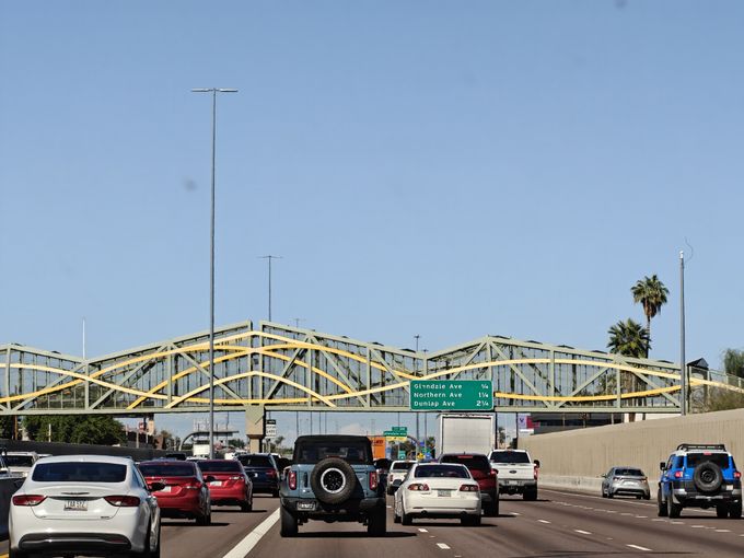 A bridge spans a highway with interesting decorative trusses.